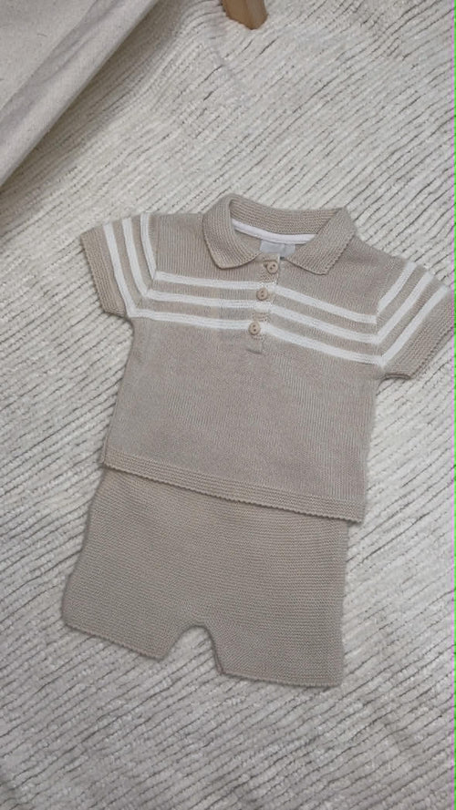 A baby knit two-piece outfit consisting of a short-sleeve polo shirt and matching shorts in a light beige colour, featuring white horizontal stripes on the sleeves and collar.
